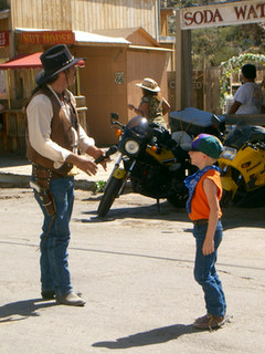 写真: ガンマンと子供、その背景の二台のバイク